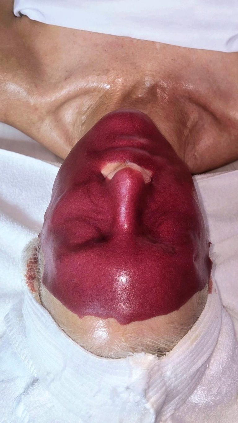 professional esthetician applying alginate jelly mask during facial treatment