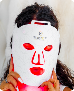 Woman wearing the ILUMILUX red light therapy mask in red light mode