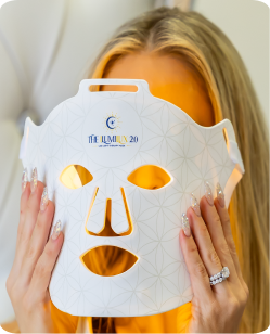 Woman wearing the ILUMILUX LED light therapy mask in amber light mode