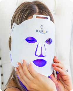 Woman wearing the ILUMILUX LED face mask in blue light mode